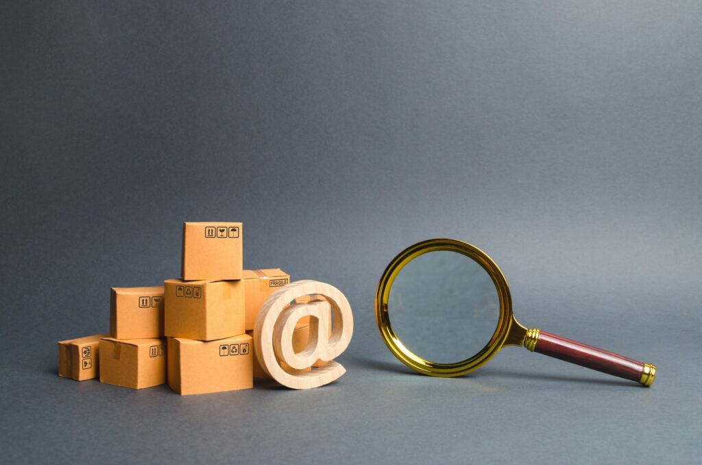 Pile of boxes with email symbol AT and a magnifying glass