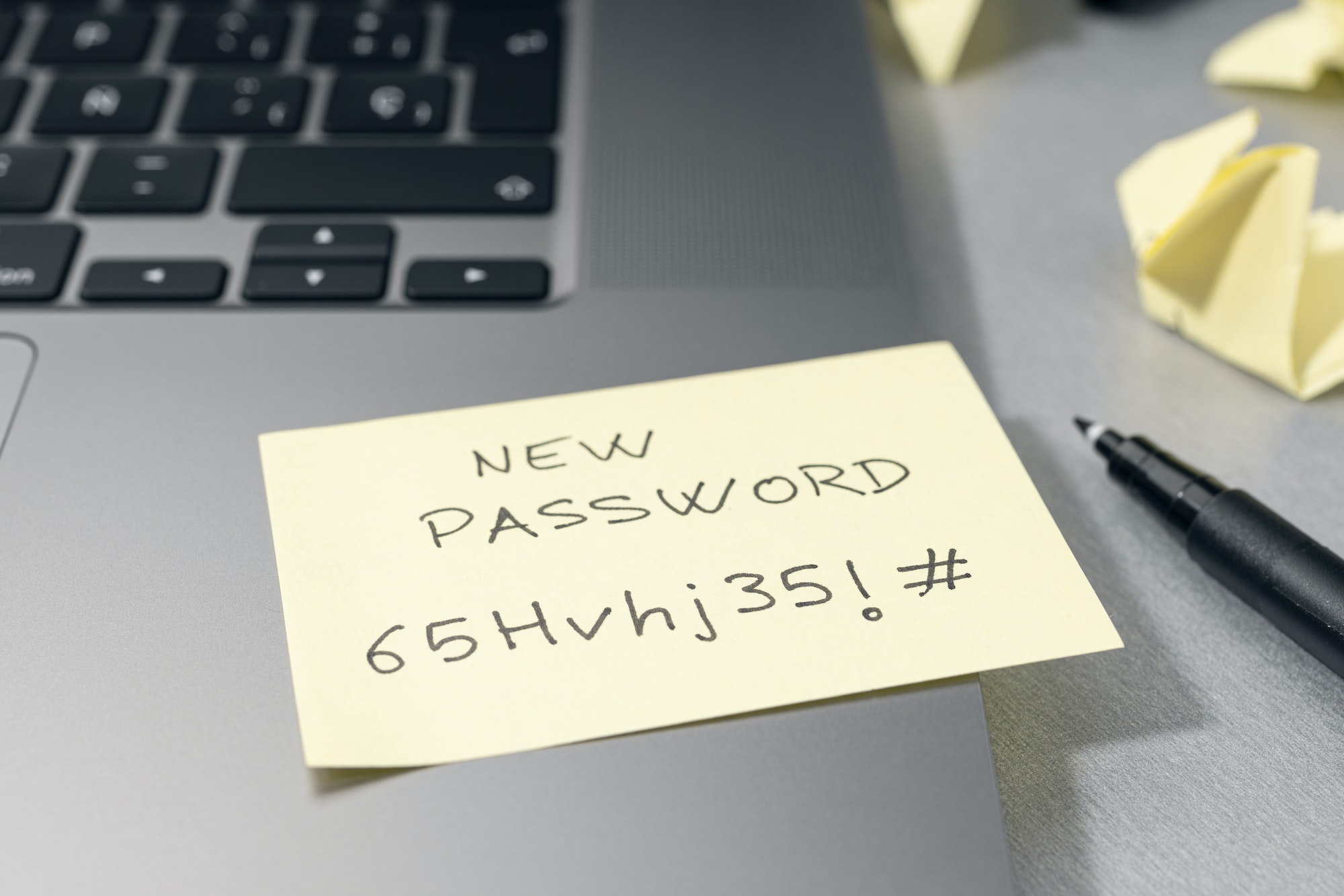 Strong password on sticky note on laptop