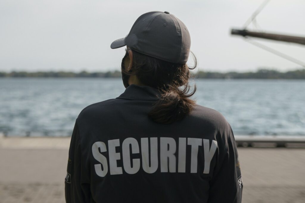 Closeup shot of a female security guard in uniform and mask watching over the harbor area